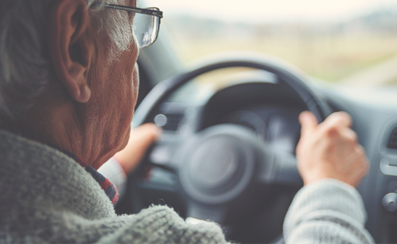 An older man driving a car.